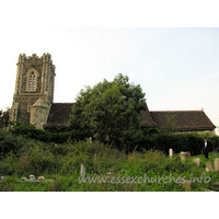 St James, West Tilbury Church – Exterior 2: The S side of the church. The lovely Julie poses for us in front of the chancel. The churchyard, or, at least, the Church of England part of it, is in a rather dilapidated state. It is a shame, as there have been some recent (1997) burials here.