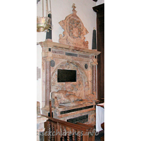 St Michael, Theydon Mount Church – Monument 1: Monument to Thomas Smith d.1577. This monument was moved from the old church. Sir Thomas is depicted 'stiffly' reclining, head propped up on elbow. There is a shallow coffered arch behind the figure, flanked by two Ionic columns, with an entablature carrying two black obelisks and the large achievement shown above. The inscription within the arched recess reads thus: Thomas Smithus Eques auratus huius Maneriu DNS, cum Regis Edvardi sexti tum Elizabatha Regina Consiliarius, ac frimi nominis Secretarius eorundemq, Principum ad maximos Reges legatus Nobiliss ordinis Garterii Cancellarius, Ardae Australisque Claneboy in Hibernia Colonellus, Iuris civilis supremo titulo etiam num Adolescens insignitus Orator, Mathematicus, Philosophus, excellentiss (vs) Linguarum Latinae, Grecae, Hebraicae, Gallicae etiam et italica callentiss (vs) Proborum et ingeniosorum hominum favtor alieniss Deniq sapientia, pietate, integritate insignis et in omni vita sev aeger sev valens intrepidus more, cum aetatis svae 05m annum compleuisset in aedibus suis Montaulensibus 12o die Augusti, Ao Salutis 1577 pie et suauiter in Domino obdormiuit