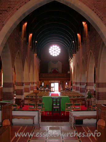All Saints, Southend-on-Sea Church – Looking west from the chancel, the high semicircular wagon type roof is just visible. The chamfered piers are decorated by alternating bands of brick and stone.