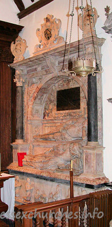 , Theydon%Mount Church - 


This standing wall-monument depicts Sir William Smith d.1626 (builder 
of the church) and his wife, Bridget. Sir William is slightly higher than, and 
behind, his wife. 

	To the pious memorie of her loved and loving husband
Sr William Smyth of Hill Hall in the County of Essex knight
who till he was xxx yeares old followeed the warres in
Ireland with such aprobation that he was chosen one
of the Colonels of the Army. But his uncle Sr Thom. Smyth
Chancellor of the Garter & Principall Secretary of
State to two princes King Edward the sixt & the late
Queene Elizabeth of famous memorie dying he returned
to a faire & full inhaeritance, and so bent himselfe to
the afaires of the countret that he grewe alike famous
in the artes of peace as warre. All offices that sorted
with a man of his quality ge right worshipfully performed
and dyed one of the Deputy Lieutenants of the Shire. A
place of no smalle trust and credit.
Bridget (his unfortunate widow who during the space
of XXXVII yeares bare him III sonnes and IIII daughters)
daughter of Thomas Fleetwood of the Vache in the County
of Buckingham Esq and sometimes Mr of the Mint to
allay her languor and longing after so deare a
companion of her life rather to expresse her affection
than his merit this monument erected destinating the
same to herself theire children and posteritie he
lived years LXXVI dyed the XII day of December 1626. 

The arched recess and background are very similar to the 
monument to his father ...

